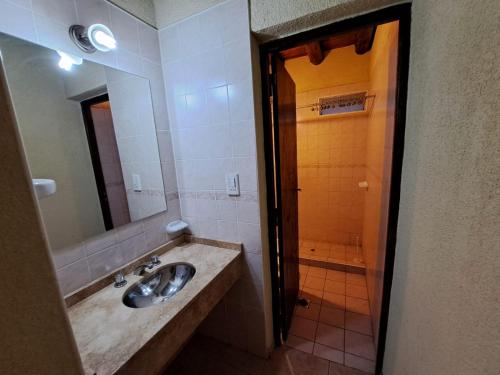 a bathroom with a sink and a shower with a mirror at CABAÑAS EL CERRO in Ciudad Lujan de Cuyo