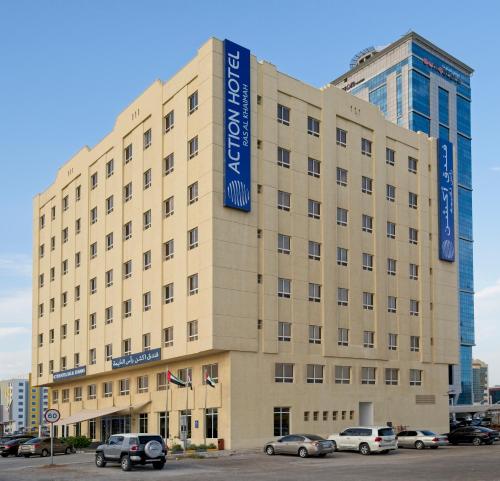 a large tan building with a blue sign on it at Action Hotel Ras Al Khaimah in Ras al Khaimah