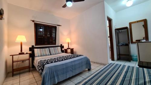 a bedroom with a bed and two lamps and a mirror at Suítes Nova Mar Ilhabela in Ilhabela