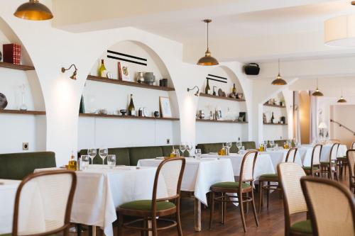 a dining room with white tables and chairs and shelves at Auberge du Rédier - Logis Hôtels in Colomars