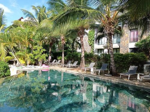 una piscina con sedie e palme e un edificio di Luxury room by Grand Vacations a Roches Noires