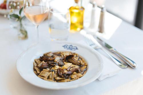 a white bowl of food on a table with wine glasses at Auberge du Rédier - Logis Hôtels in Colomars