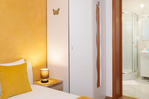 a bedroom with a bed with a yellow pillow and a bathroom at Vila Panorama in Malinska