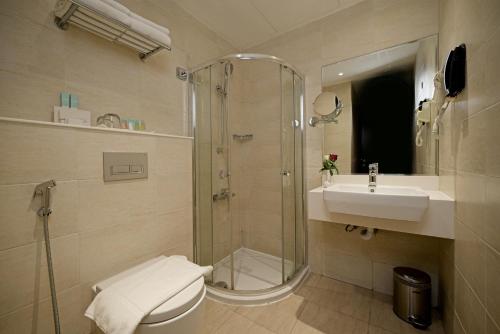 a bathroom with a shower and a toilet and a sink at Action Hotel Ras Al Khaimah in Ras al Khaimah