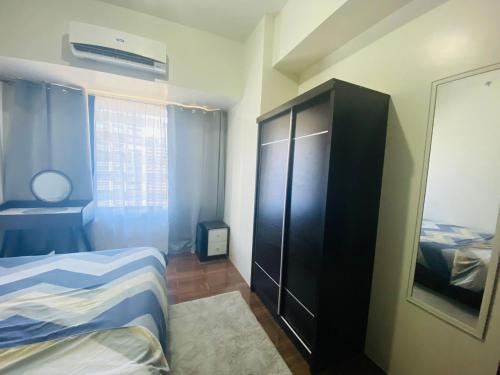 ein Schlafzimmer mit einem Bett und einem schwarzen Schrank in der Unterkunft Air Residences 1-Bedroom condo in Makati in Manila