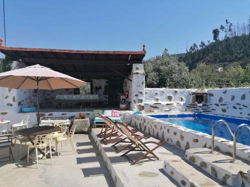 a pool with a table and chairs and an umbrella at A Cancela House Arouca Paiva Walkways in Lázaro