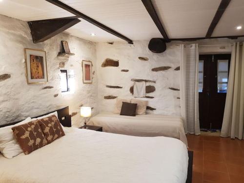 1 dormitorio con 2 camas y pared de piedra en A Cancela House Arouca Paiva Walkways, en Lázaro