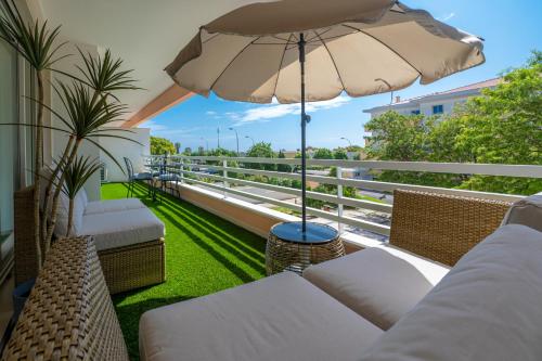 einen Balkon mit Sofa und Sonnenschirm in der Unterkunft Belo Horizonte Apart in Parede