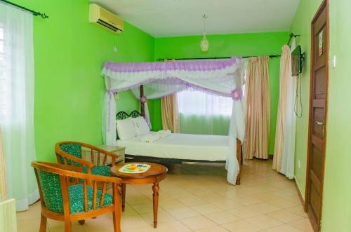 um quarto com uma cama, uma mesa e uma cadeira em Makwetu Villas em Mombasa
