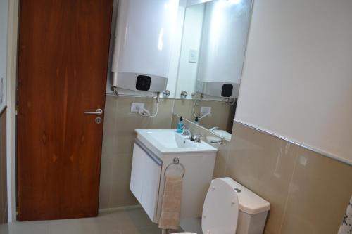 La salle de bains est pourvue de toilettes, d'un lavabo et d'un miroir. dans l'établissement Calmo Dooneo Appart La Plata - Departamentos con COCHERA, à La Plata