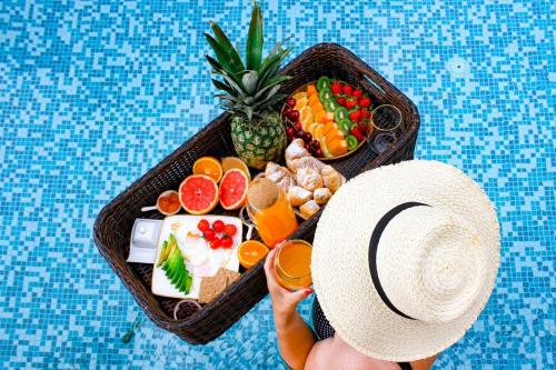 a person with a hat and a tray of food at Harmonia Bungalows & Pool in Sveti Stefan