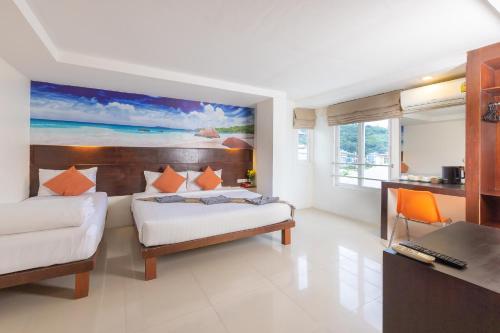 Habitación de hotel con cama, escritorio y escritorio. en Patong Buri Resort, en Patong Beach