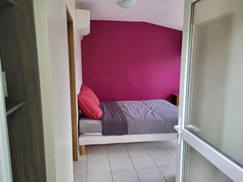 a small bedroom with a pink wall and a bed at chambre avec vue in Duilhac