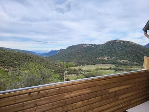 a person standing on a wooden deck looking at the mountains at chambre avec vue in Duilhac