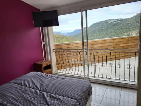 1 dormitorio con balcón con cama y ventana grande en chambre avec vue en Duillac