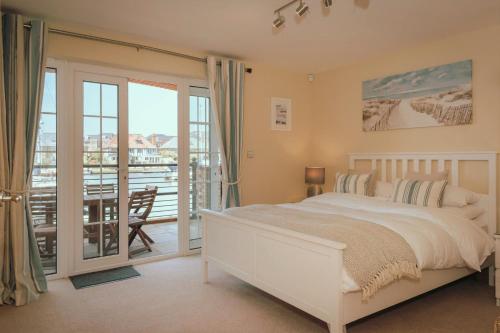 a bedroom with a white bed and a balcony at Harbour Views at Silver Strand in Pevensey