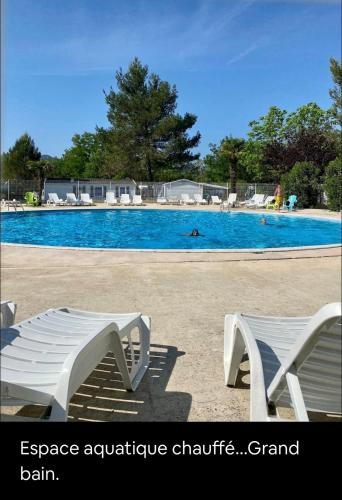 - une piscine avec deux chaises blanches devant dans l'établissement La Paillote de Claire, à La Roque-dʼAnthéron