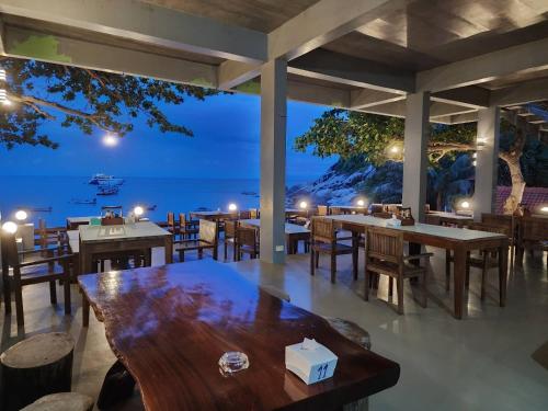 a restaurant with tables and chairs and a view of the ocean at Mountain Reef Beach Resort in Ko Tao
