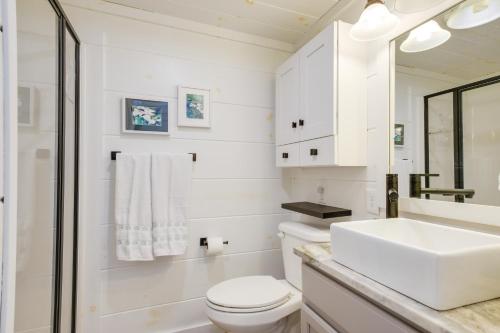 a white bathroom with a sink and a toilet at Chic Flat Rock Tiny Home with Community Pool Access! in Flat Rock