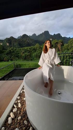 a young girl sitting in a bath tub on a balcony at Phu Siab Mhok@KhaoSok in Khao Sok
