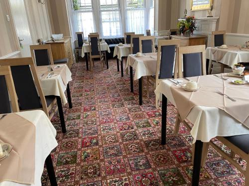 een restaurant met tafels en stoelen met witte tafelkleden bij The Sandrock in Clacton-on-Sea