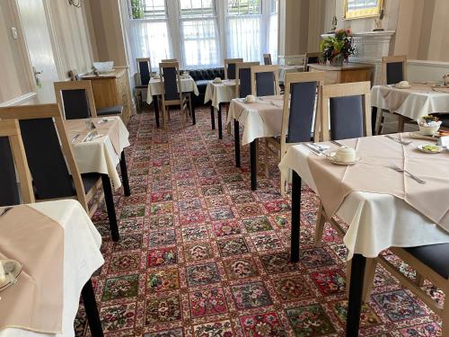 クラクトン・オン・シーにあるThe Sandrockの白いテーブルクロスのテーブルと椅子が備わるレストラン