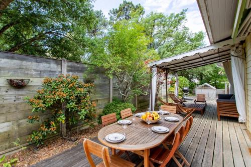 una terraza de madera con mesa y sillas de madera en Villa des Sables, en Lège-Cap-Ferret