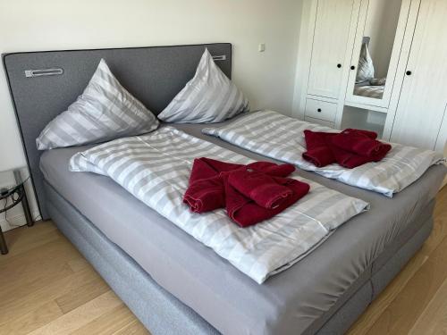 two beds with red pillows on top of them at Linnenboom - lichtdurchflutete Neubauwohnung für gehobene Ansprüche in Wangerooge
