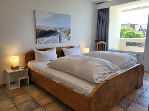 - une chambre avec un lit doté de draps blancs et une fenêtre dans l'établissement Ferienwohnung 58 im Haus Villa Anna, à Sankt Peter-Ording