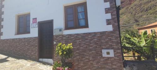 a house with a brick wall and two windows at Casa Pepito in Agulo