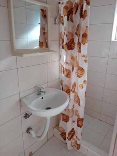 a bathroom with a sink and a shower curtain at Studio apartmani Dream Iv in Šušanj