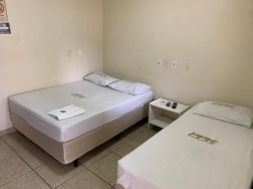 two beds in a small room with white walls at Pissin Plaza Hotel in Goiânia