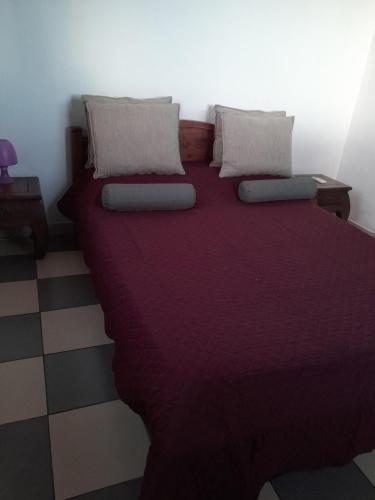 a bedroom with a large bed with purple sheets and pillows at Le Refuge in Saint-Leu