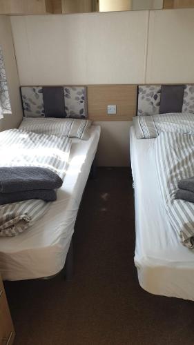 Holiday Lodge, sleeps 4, with sea & countryside views في Ore: سريرين توأم في غرفة صغيرة بها