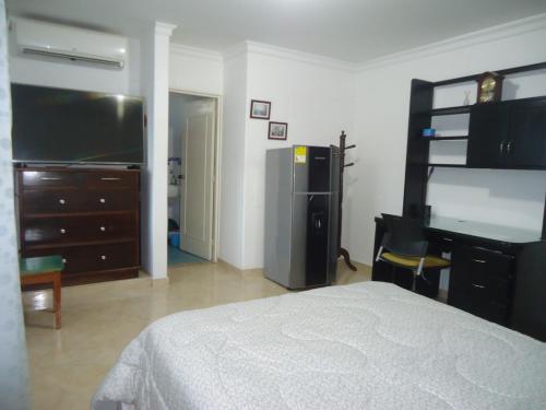 um quarto com uma cama, uma secretária e uma televisão em Habitación privada em Neiva