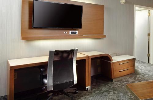 a room with a desk with a chair and a television on a wall at Courtyard by Marriott State College in State College