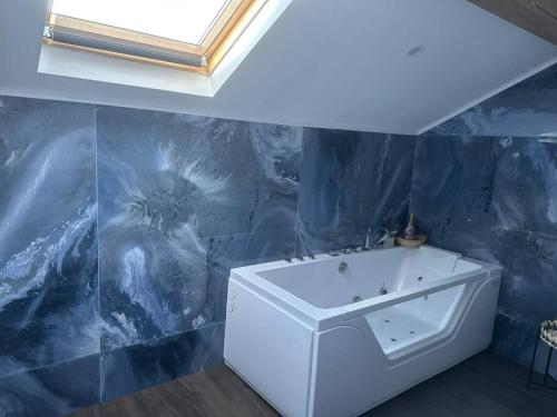 La salle de bains est pourvue d'un lavabo blanc et d'un mur bleu. dans l'établissement Villa Jacqueline, à coutances