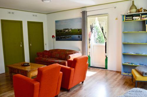 a living room with orange chairs and a table at Het Melkhuis op prachtig Landgoed Koepeltjesplaats in Gaast