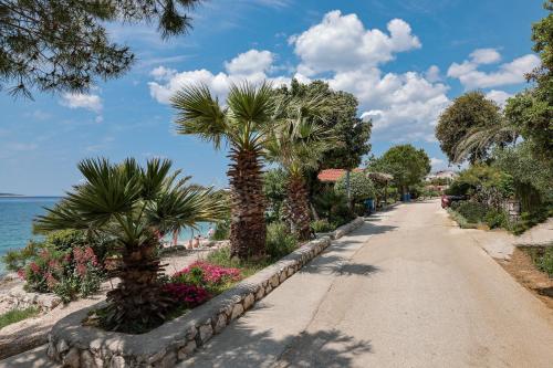 a street with palm trees and flowers next to the ocean at Chill 4 Real Sea View Mandre in Mandre