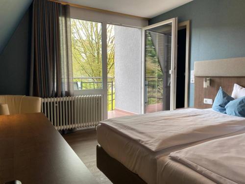 a bedroom with a bed and a large window at Hotel Cafe Gästehaus Stefanie in Partenstein