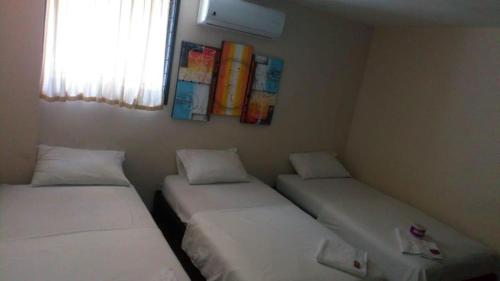 two beds in a small room with a window at EL Dorado Hotel Maicao in Maicao