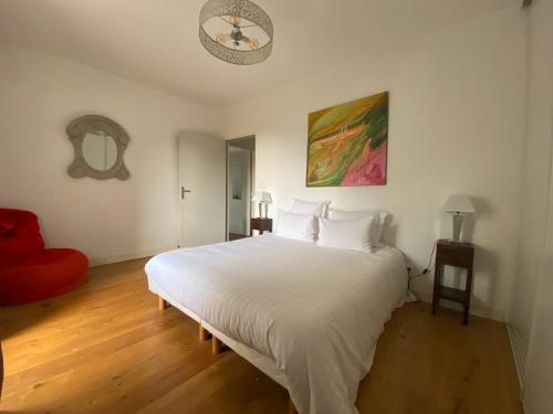 um quarto com uma cama branca e uma cadeira vermelha em Coeur Cité Médiévale Appart' 2- 4 personnes "La Salamandre" 80 m2 à 20m de la Mairie em Sarlat-la-Canéda