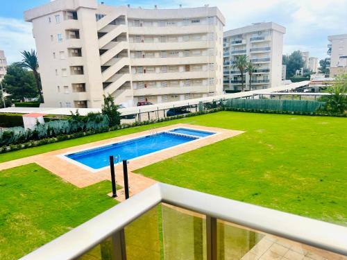 a swimming pool in a grassy area next to a building at Apartamento con Piscina y Jardín Espectacular Cala Sirenas - Nuevo in Miami Platja
