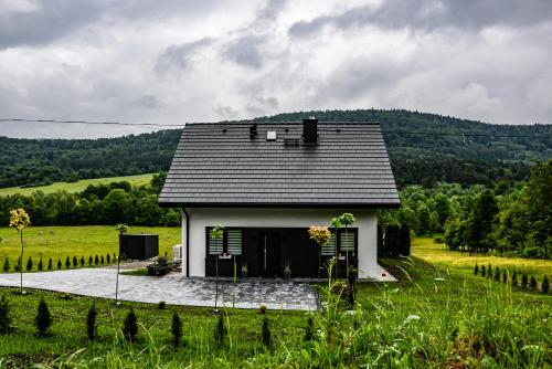 una pequeña casa blanca en un campo con árboles en Domek Veron en Wysowa-Zdrój