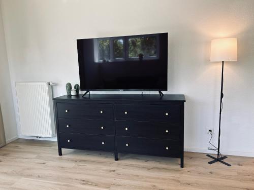 uma cómoda preta com uma televisão de ecrã plano por cima em FeWo Am Ring - mit Terrasse em Nordhorn