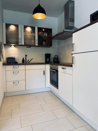 a kitchen with white cabinets and a refrigerator at FeWo Am Ring Neubau & Terrasse in Nordhorn