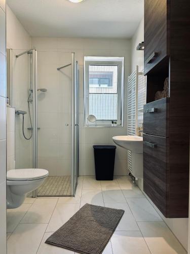 a bathroom with a shower and a toilet and a sink at FeWo Am Ring Neubau & Terrasse in Nordhorn