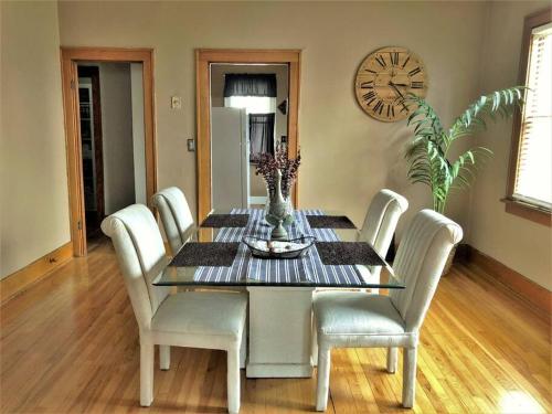 a dining room table with white chairs and a clock at Home near Zoo/College World Series/Downtown in Omaha