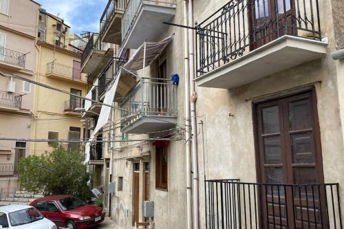 un edificio con balcones y coches aparcados en una calle en Tenuta Balabaia, Townhouse. en Caccamo