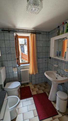 baño con 2 aseos, lavamanos y ventana en La Cleyva, en Valpelline